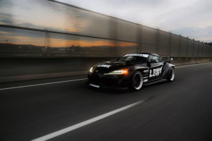 A fast black sports car races down the highway.