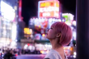 Woman gazes at bright neon signs in the city.