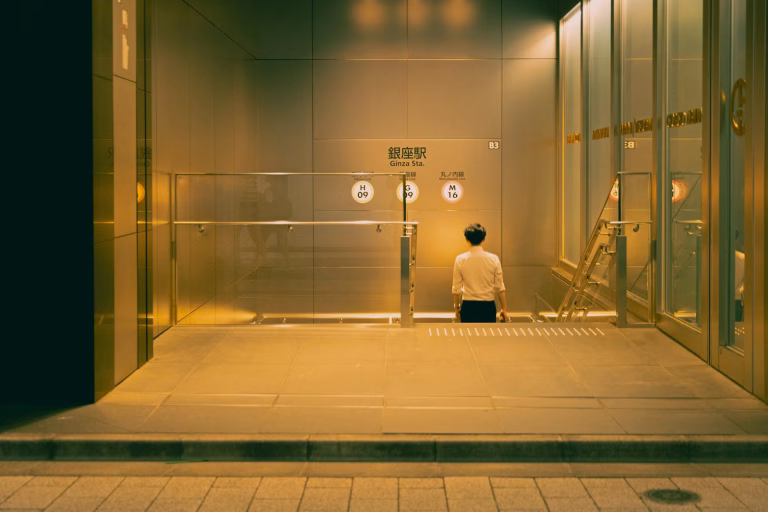 A person is sitting alone in a lit entryway.