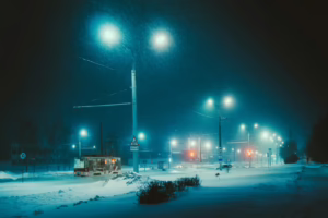 Streetlights illuminate a snowy road at night.